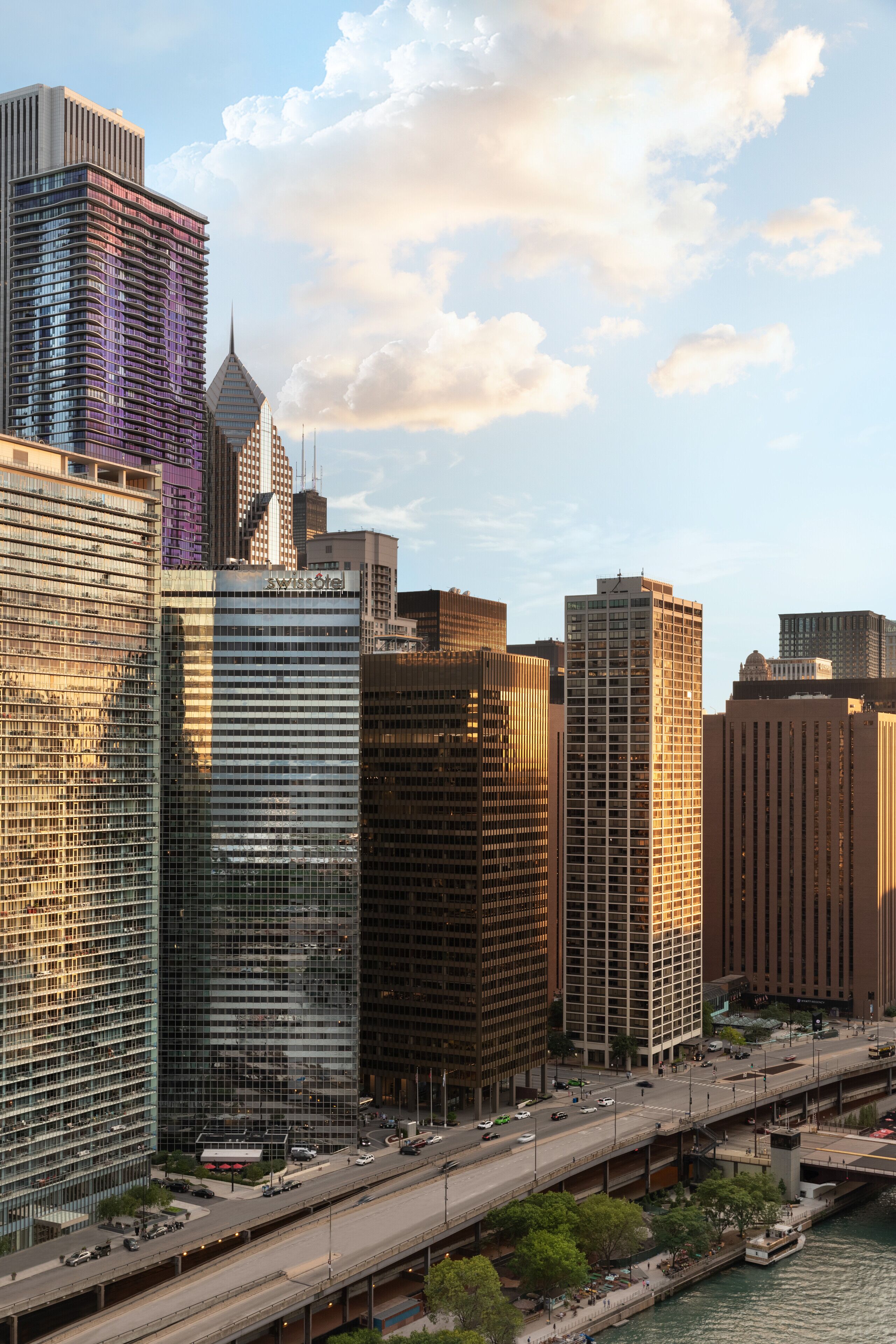 A cityscape with modern high-rise buildings, a river, and a bridge.