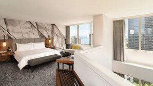 A modern hotel room with a large bed, a desk, a chair, and a view of the cityscape through large windows. - Swissotel - Chicago (Chicago)