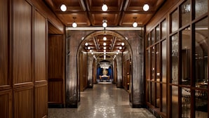 A long, narrow hallway with wooden paneling and large windows on one side. - Fairmont Royal York (Toronto)