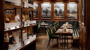 A restaurant with wooden shelves, green upholstered booths, and a view of a landscape through large windows.