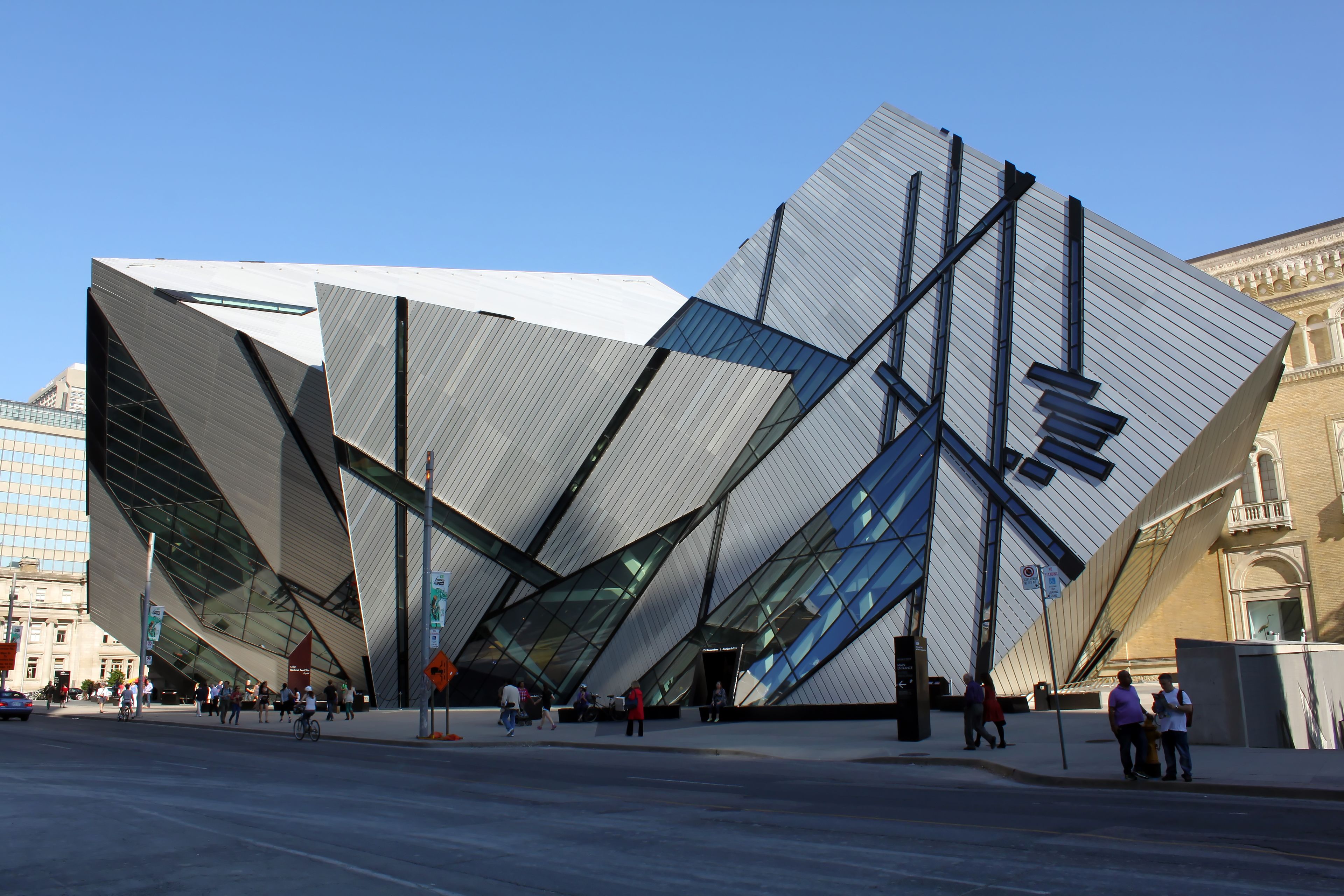 A modern building with a unique angular design, featuring large glass panels and a prominent entrance.