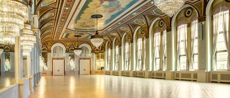 Un salón espacioso con techos altos, candelabros ornamentales y ventanas amplias.