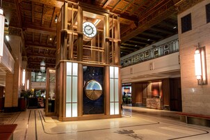 Een lobby met een centrale klokkentoren, een receptiebalie en een marmeren vloer.