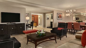 A spacious living room with a flat-screen TV, dark wood furniture, and a red accent chair.