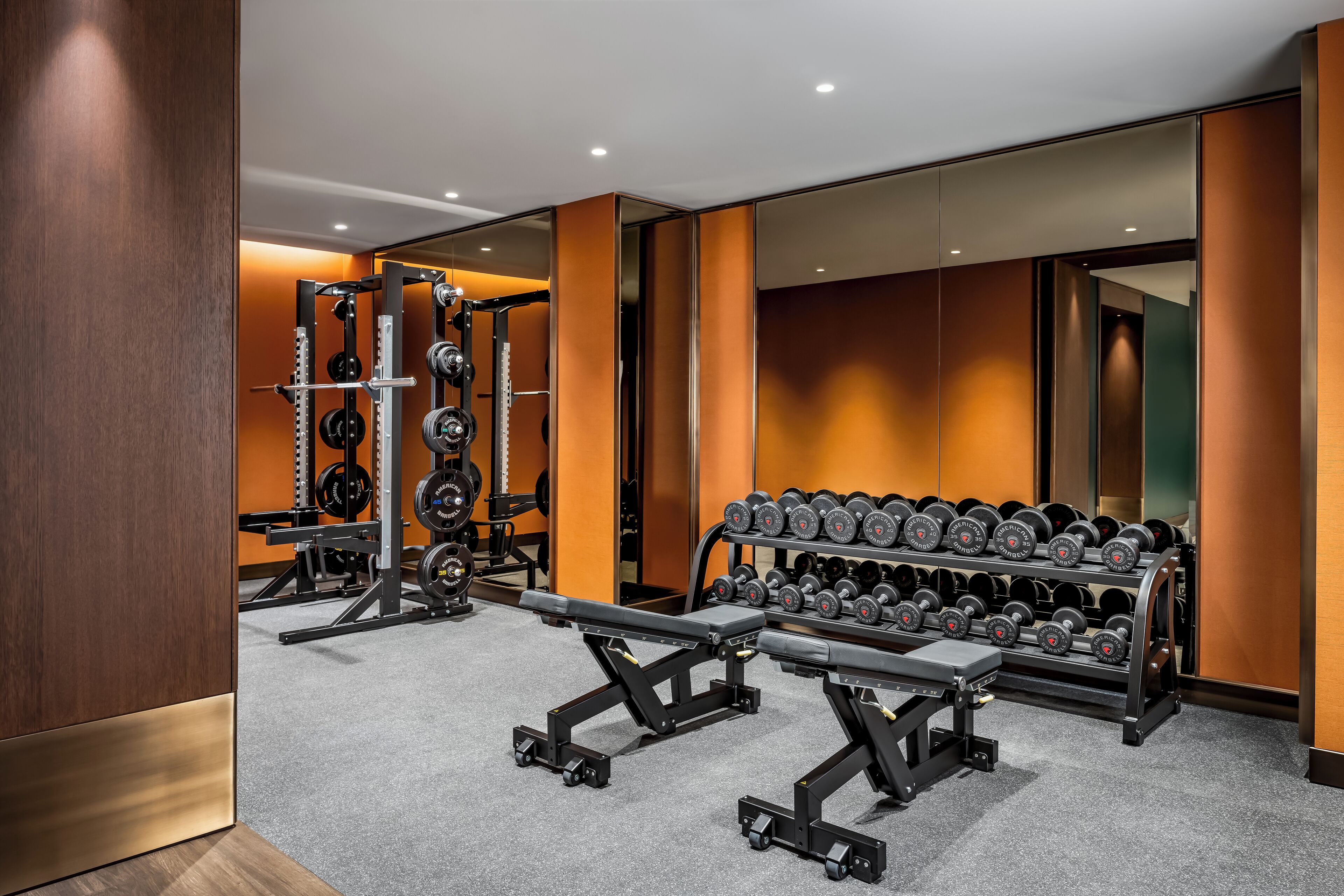 Een moderne sportschool met gewichthefapparatuur, een bankdrukpers en een rek met dumbbells.