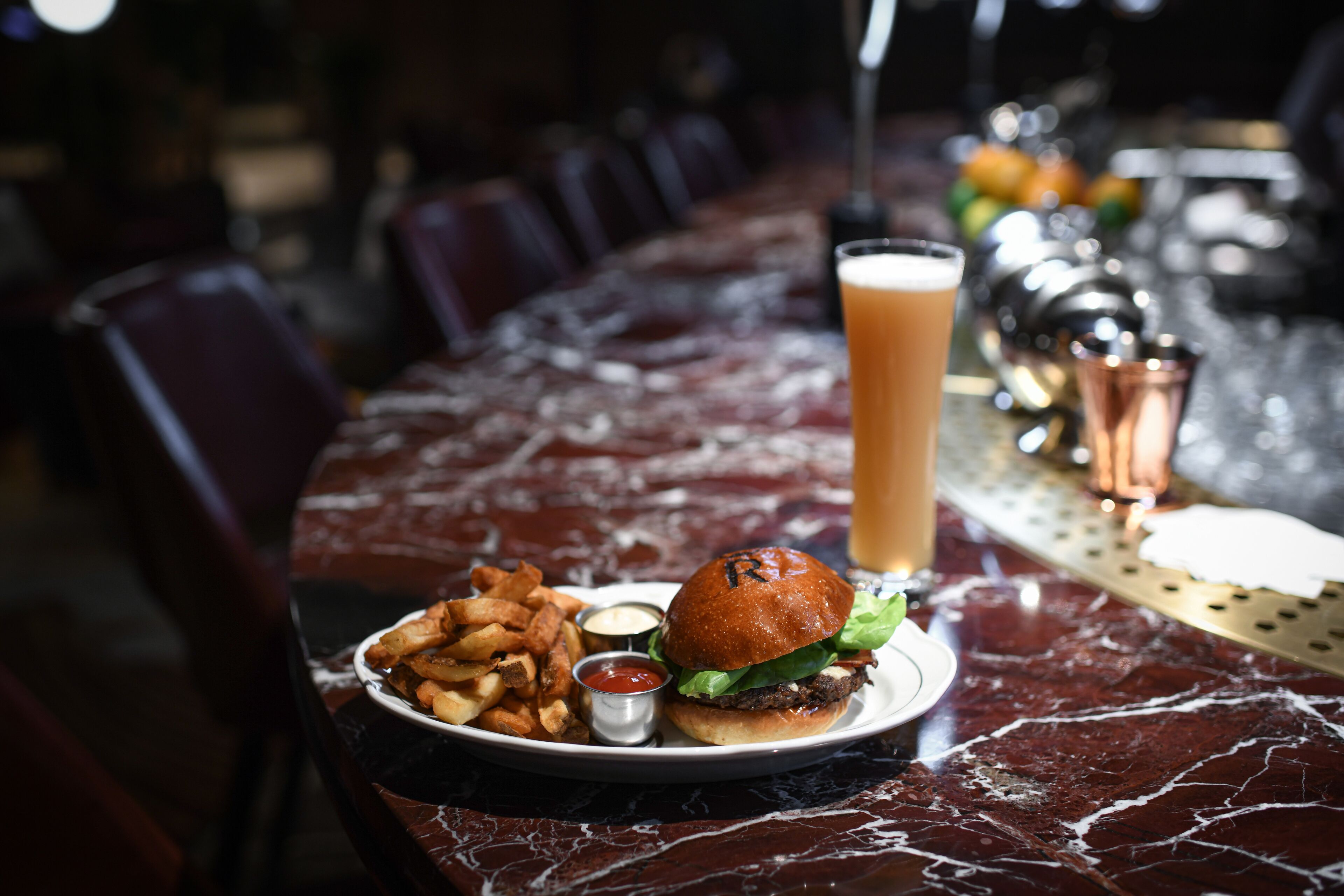 Een eettafel met een hamburger, friet en drankjes.