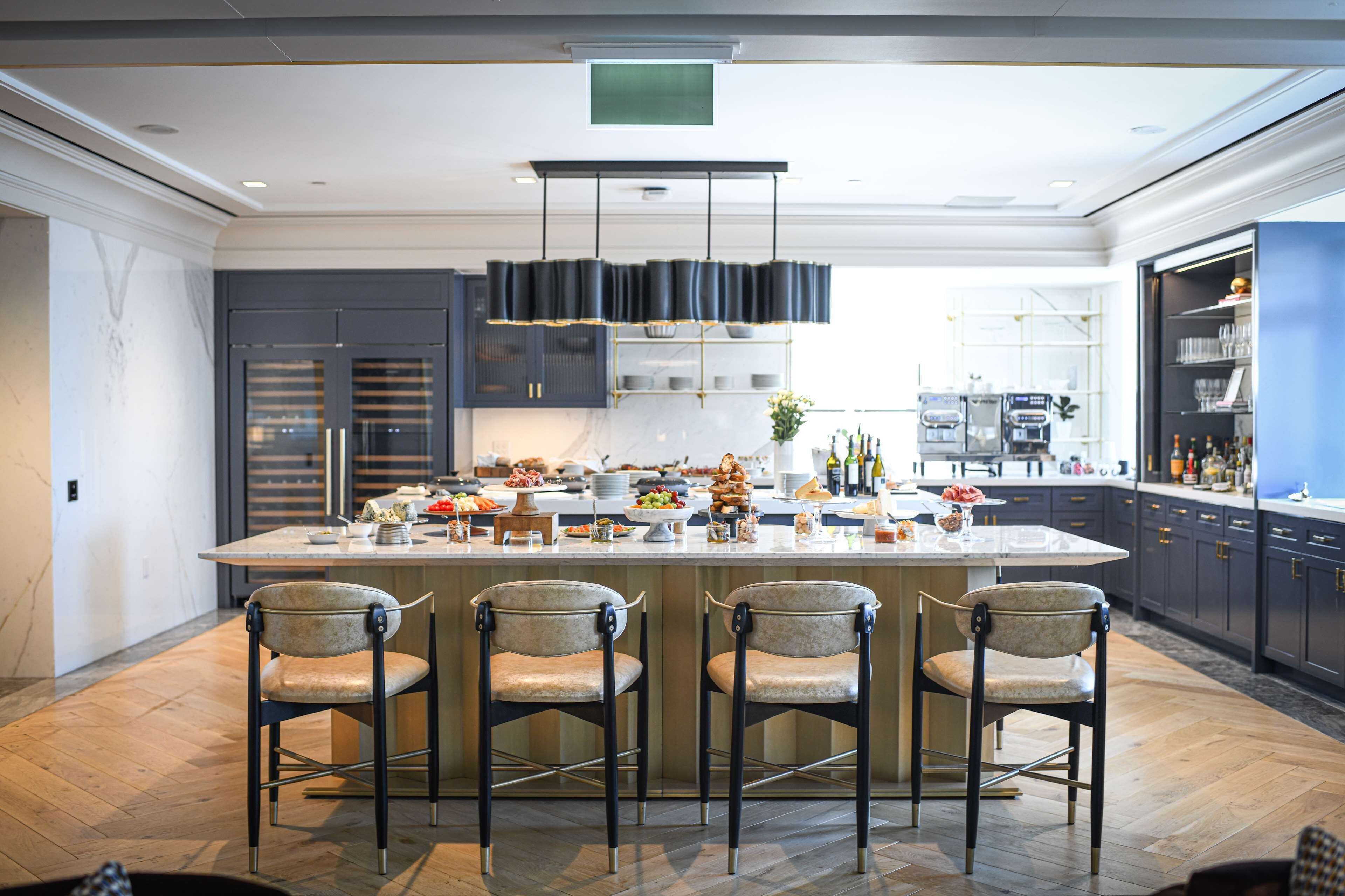 Una cocina moderna con una isla central, taburetes de bar y un enfriador de vino integrado.