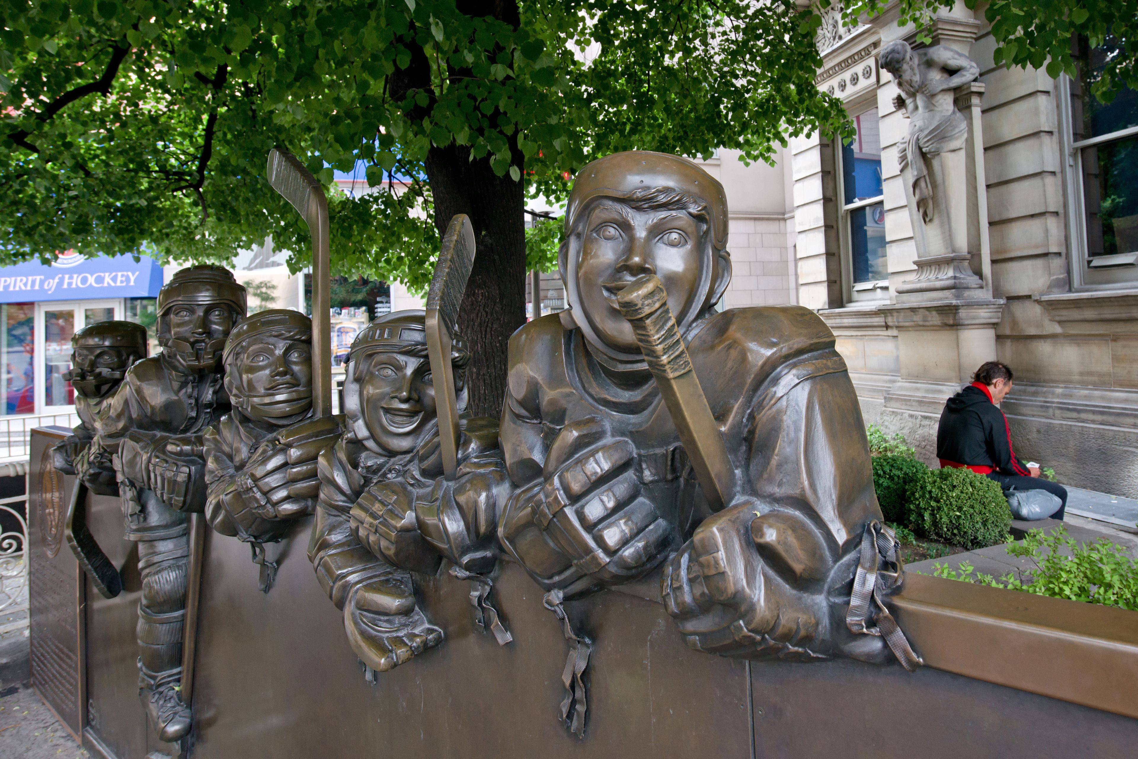 Une sculpture en bronze représentant des joueurs de hockey, installée dans un espace public.
