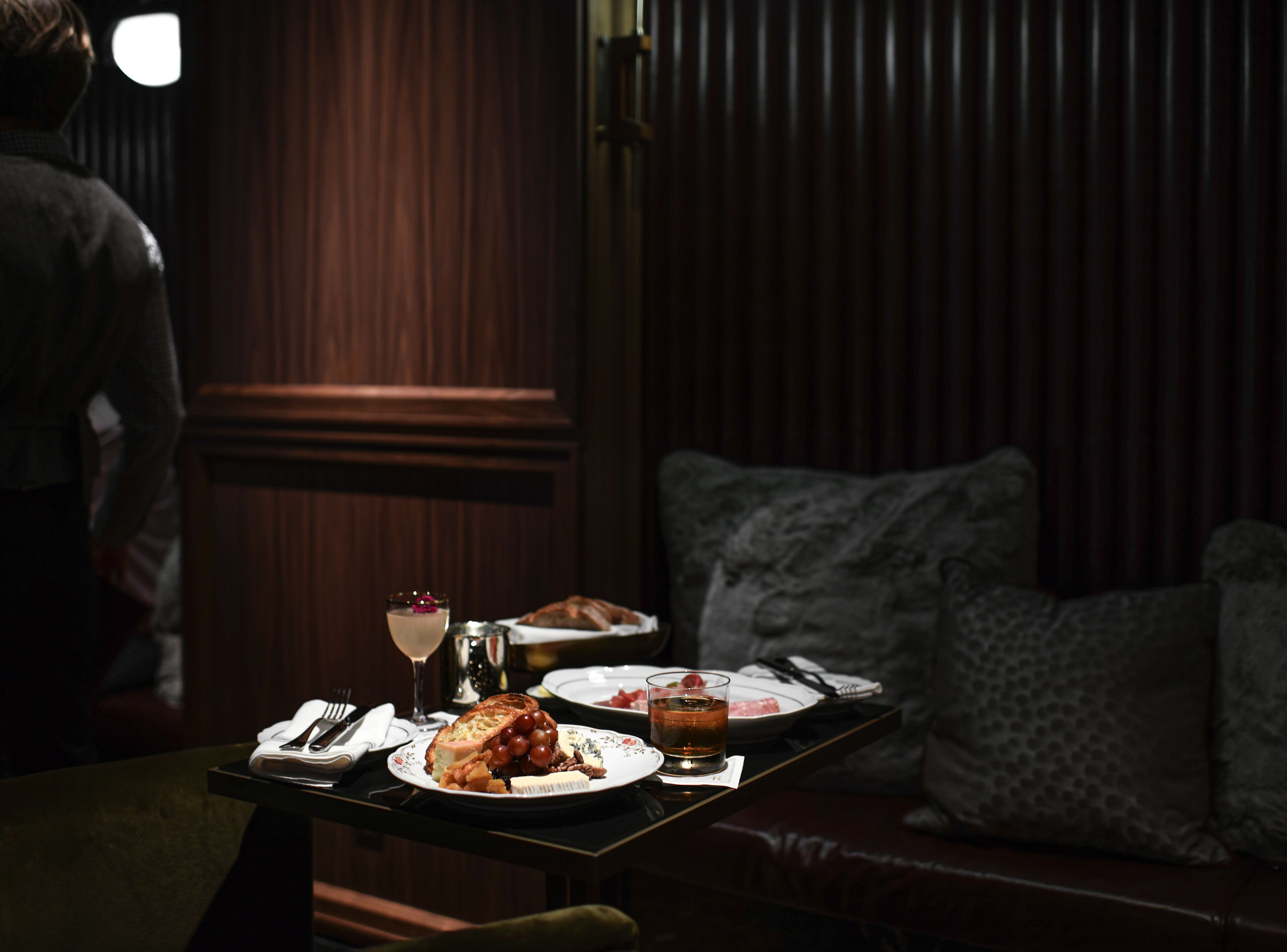 A dining table with plates of food, a glass of wine, and a bottle of water.