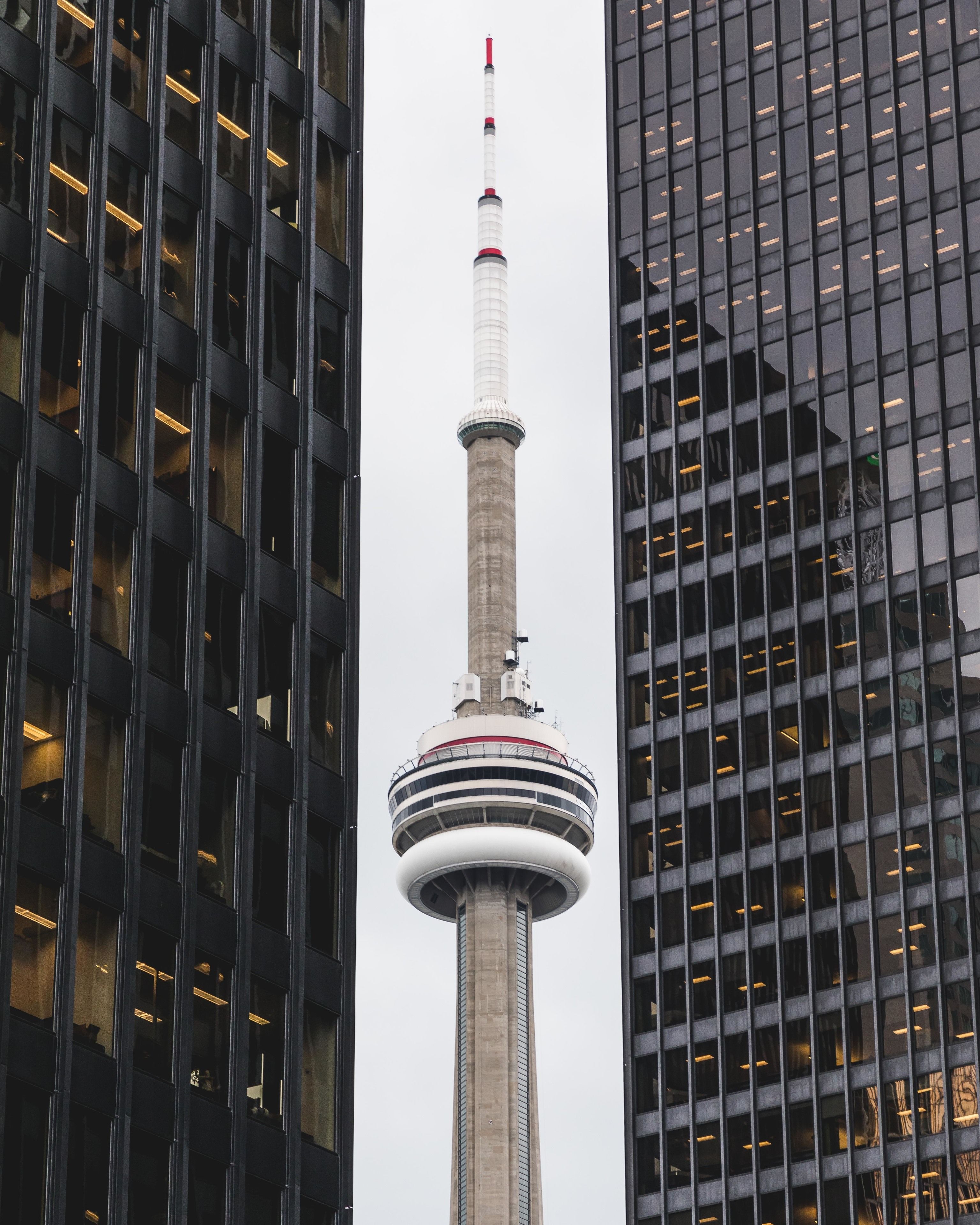 Una torre alta con una plataforma de observación circular, rodeada de edificios modernos con fachadas de vidrio reflectante.