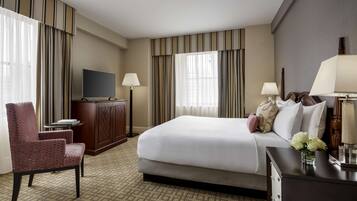 A hotel room with a bed, a TV, a desk, a chair, and a lamp.
