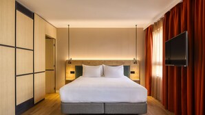 Una habitación de hotel con una cama grande, suelo de madera, televisión y armario.
