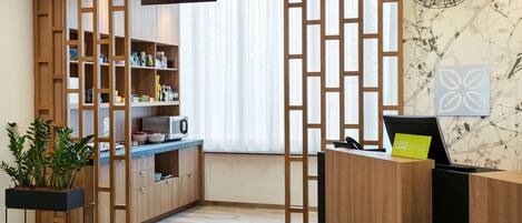 Un área de recepción con un escritorio de madera, una computadora y un cartel que indica una despensa.