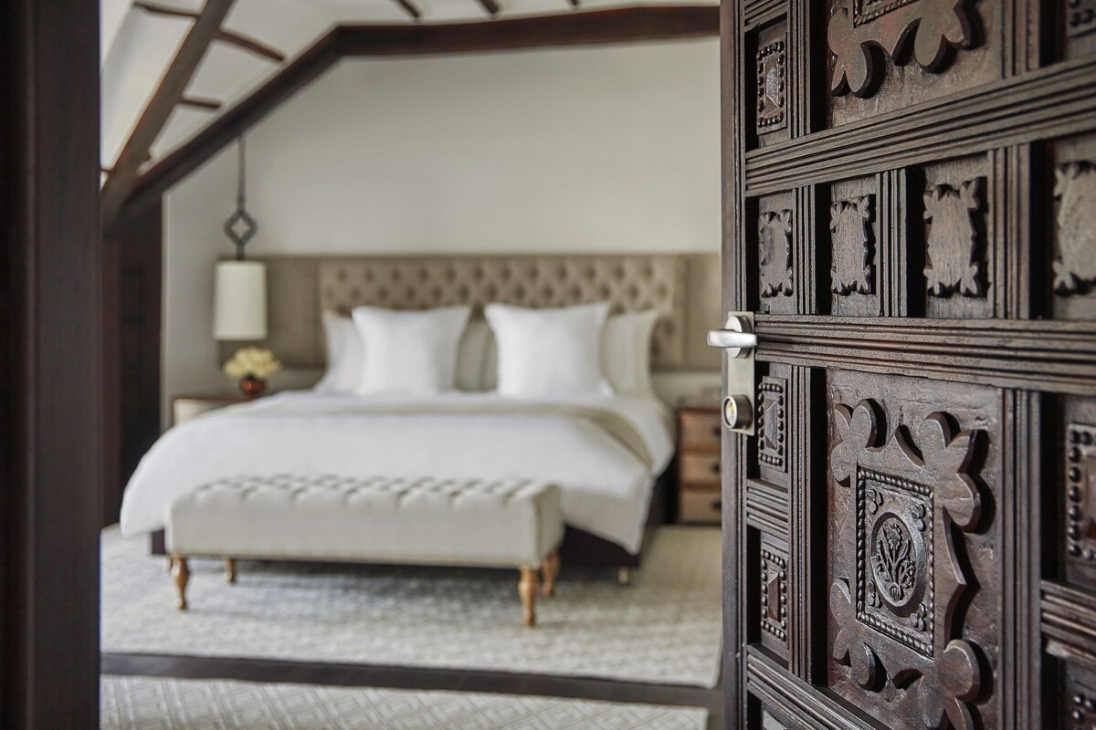 Une chambre à coucher avec un grand lit, une table de chevet et une porte en bois décorative.