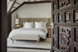 A bedroom with a large bed, a nightstand, and a decorative wooden door.