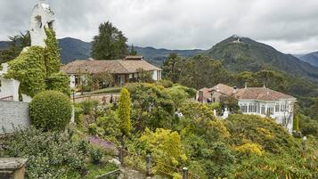 A hillside with traditional buildings, a bell tower, and lush greenery.