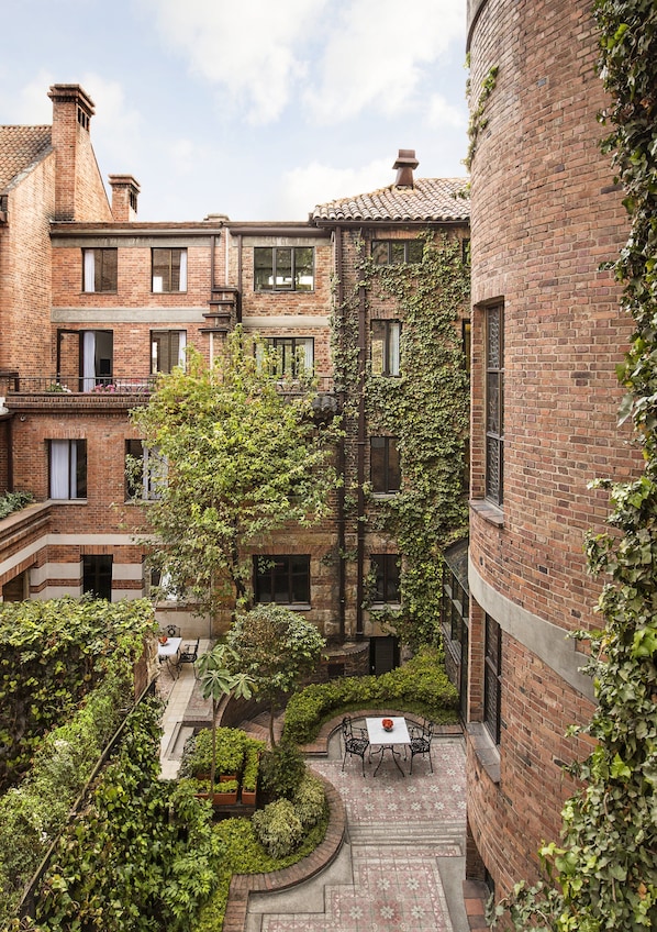 A courtyard with brick buildings, a tree, and a table with chairs.