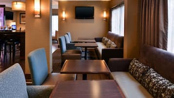 A hotel lobby with seating areas, a bar, and a television mounted on the wall.