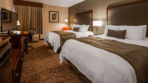 A hotel room with two beds, a desk, a chair, a television, and a carpeted floor.