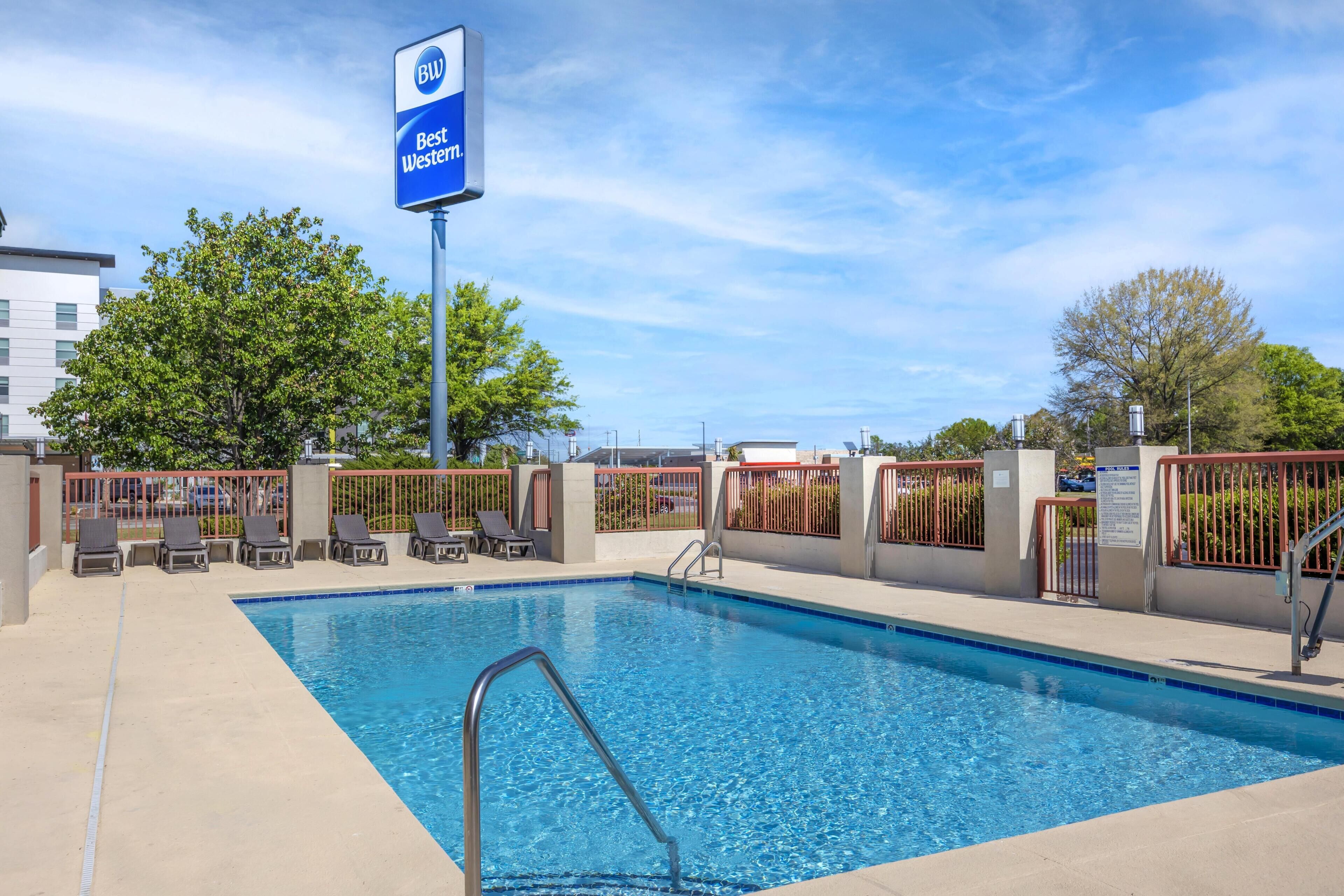 Une piscine avec des chaises longues et une enseigne Best Western.