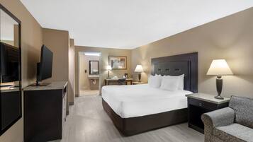Una habitación de hotel con una cama, televisión, escritorio, silla y lámpara.