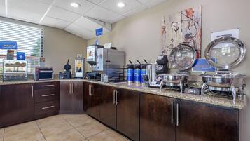 Una cocina equipada con refrigerador, microondas, cafetera y diversos electrodomésticos de cocina.