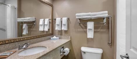 A bathroom with a sink, mirror, towel rack, toilet, and a door.