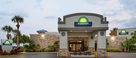 A Days Inn by Wyndham with a stone facade, palm trees, and a clear sky.