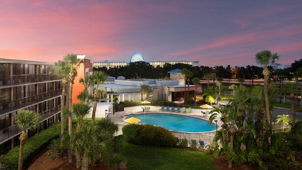 Un hotel con piscina, palmeras y un gran edificio con una cúpula al fondo.