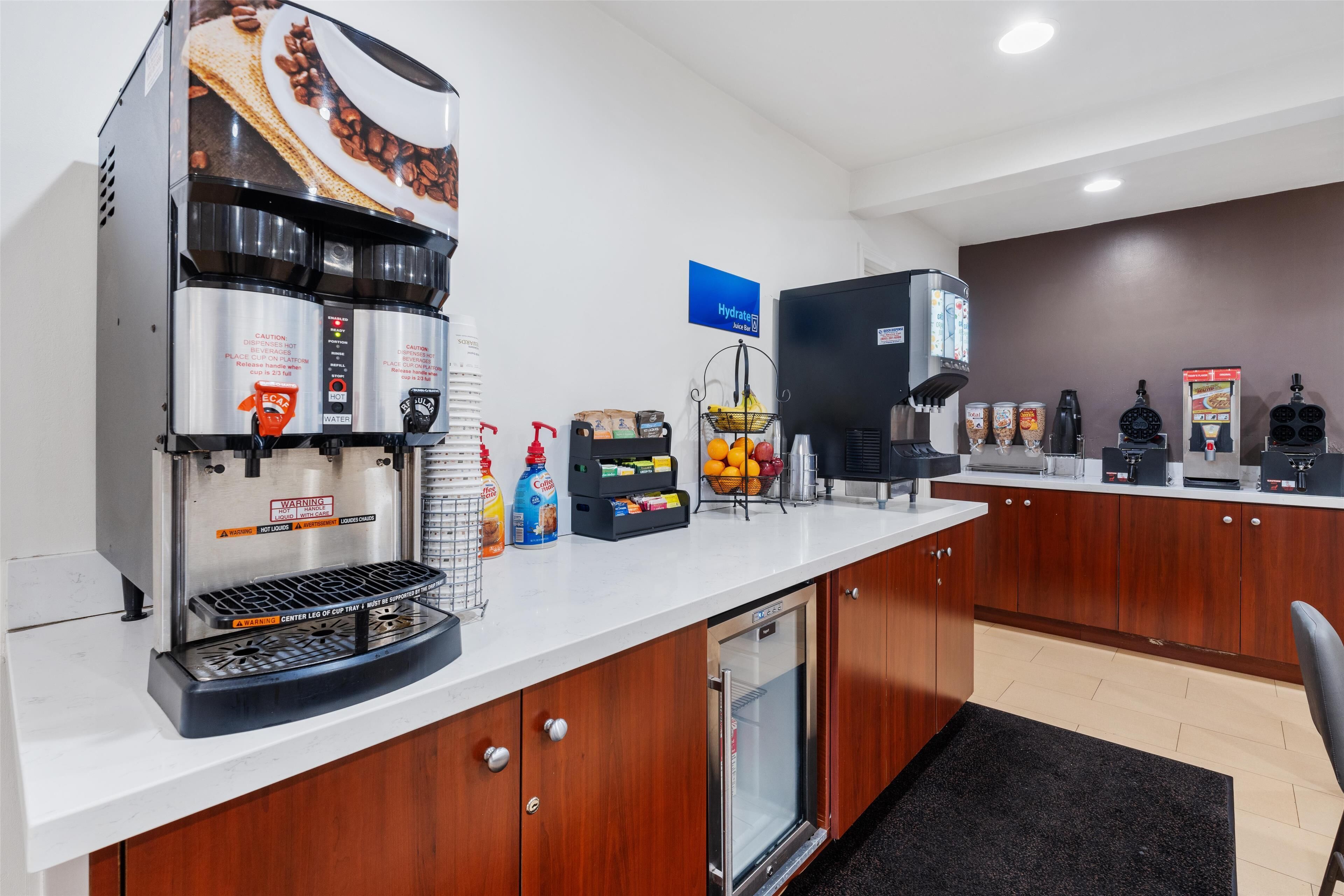 A modern kitchen with a coffee machine, refrigerator, and various food items on the counter.