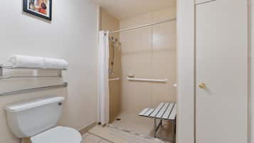 Un baño con inodoro, ducha con puerta de cristal, toallero y una puerta con manija.
