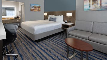 A hotel room with a bed, a sofa, a desk, and a chair.