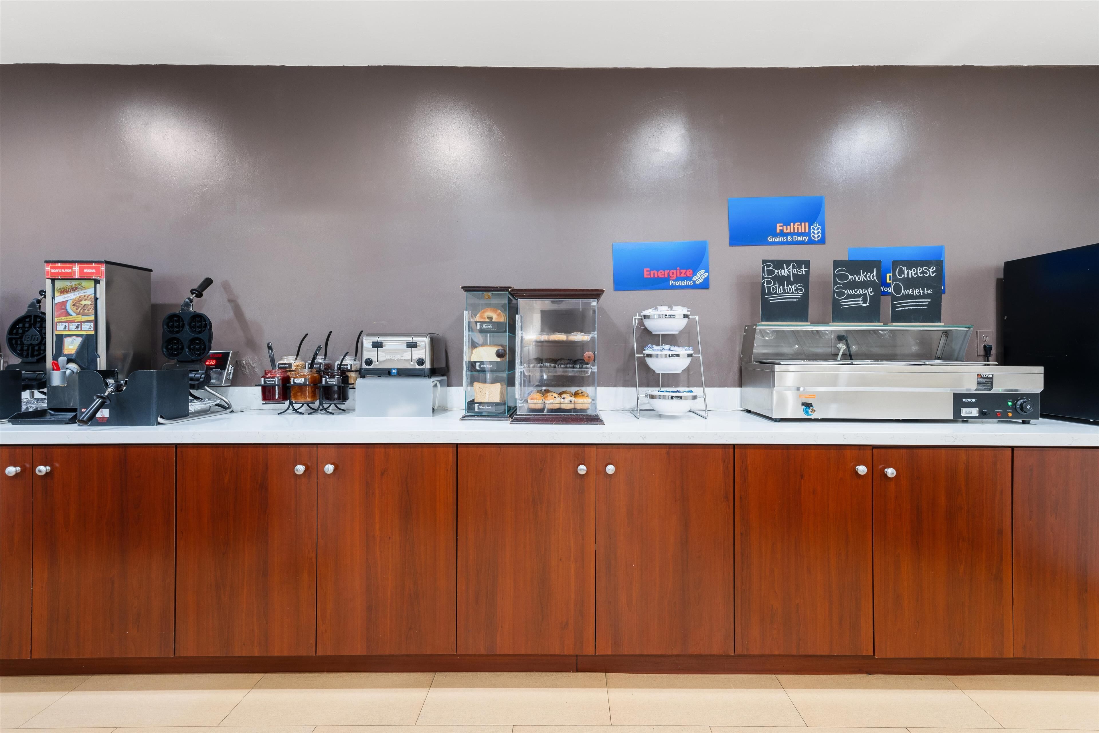 Ein Frühstücksbuffet mit Waffelmaschinen, einer Kaffeemaschine und verschiedenen Speisenauslagen.