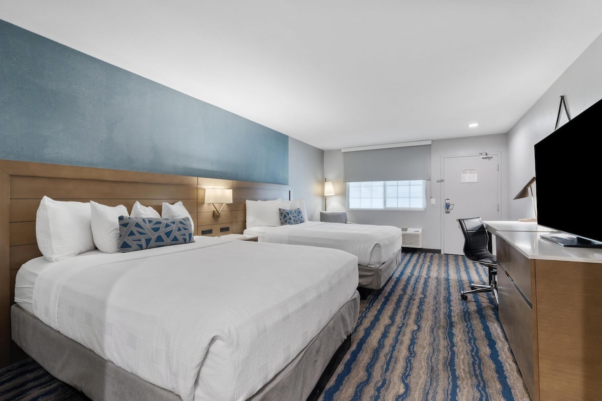 Een hotelkamer met twee bedden, een bureau en een televisie.