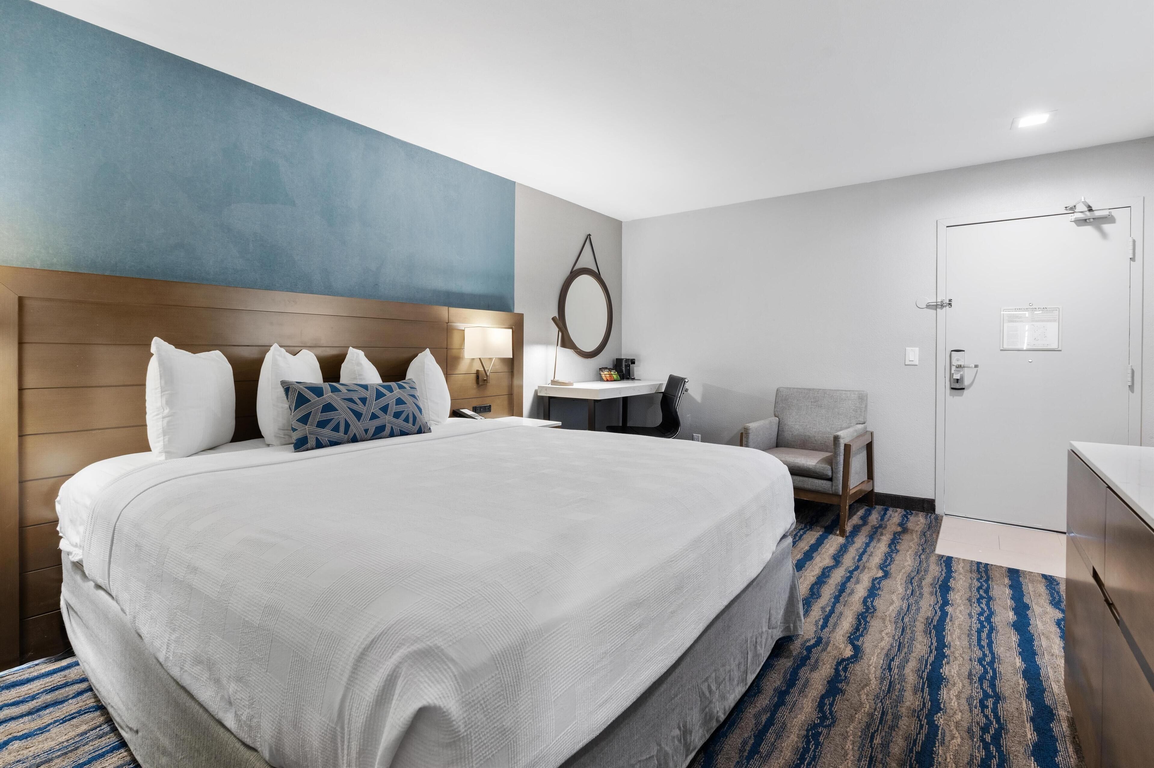 Una habitación de hotel con una cama grande, un escritorio, una silla y una puerta.