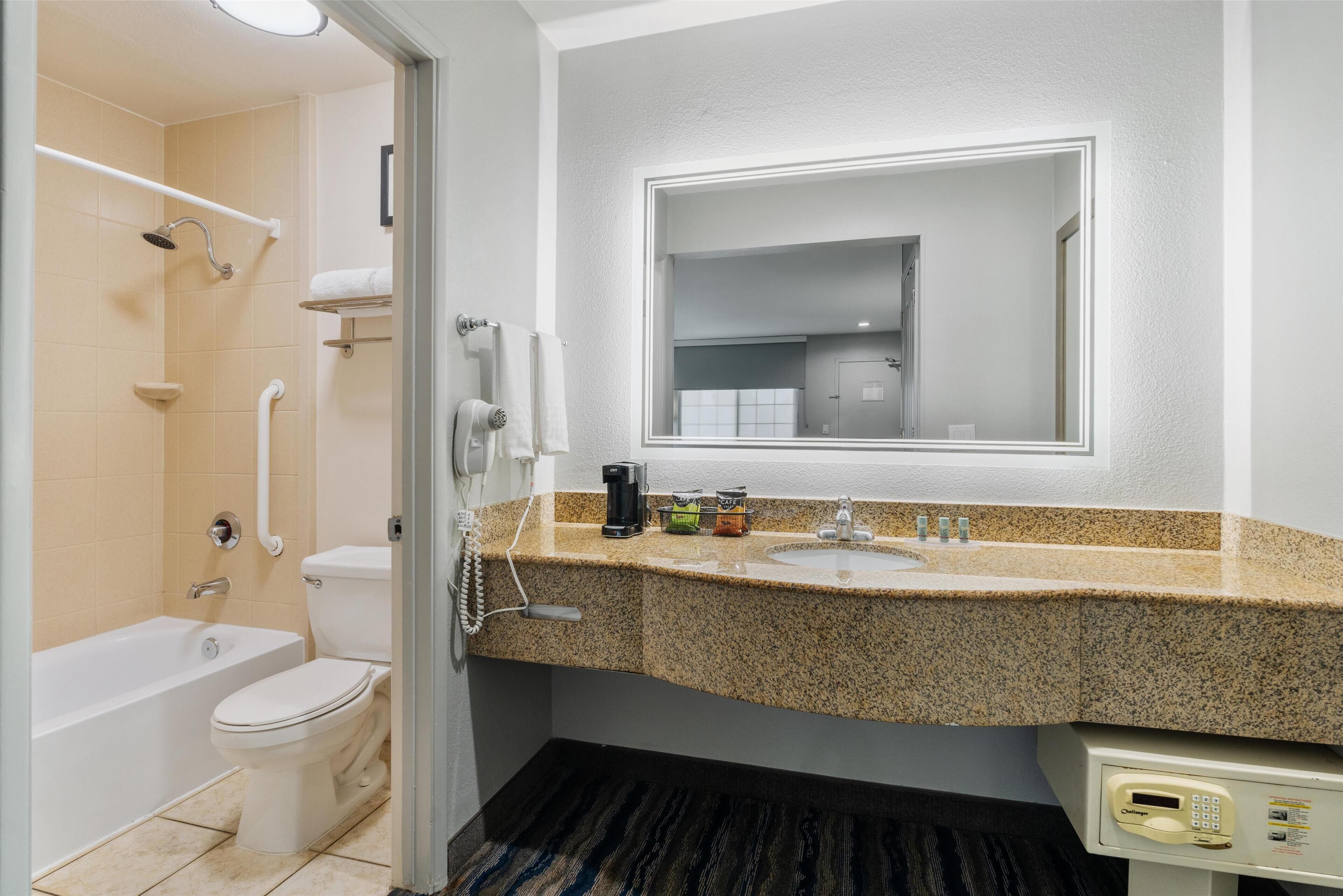 A bathroom with a bathtub, toilet, sink, and a mirror.