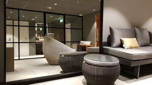 A modern lounge area with a sofa set, two wicker chairs, and a glass coffee table. - Bilderberg Parkhotel Rotterdam (Rotterdam)