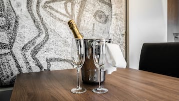 Una mesa de madera con dos copas de champán vacías y una botella de champán en un cubo de metal.