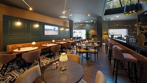 A modern restaurant with high tables, booths, and bar seating. - Bilderberg Parkhotel Rotterdam (Rotterdam)