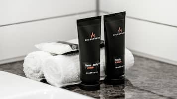 Dos botellas negras de loción corporal y una toalla blanca sobre una encimera de baño.