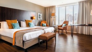 A hotel room with a large bed, two chairs, a desk, and a view of the city. - Bilderberg Parkhotel Rotterdam (Rotterdam)
