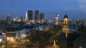 A cityscape at dusk with illuminated buildings, a prominent clock tower, and a modern bridge.