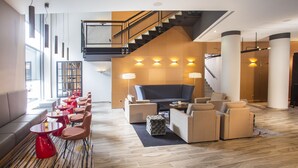 A modern lobby with a staircase, seating area, and a large TV screen. - Bilderberg Parkhotel Rotterdam (Rotterdam)