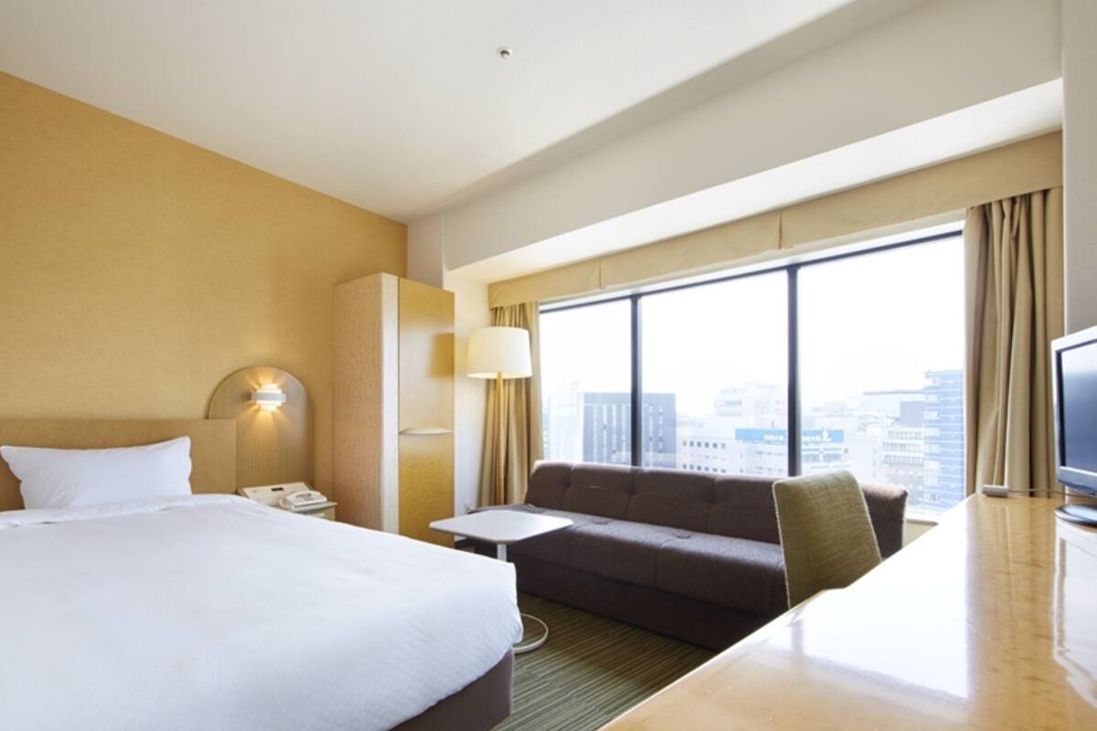 Ein Hotelzimmer mit einem großen Bett, einer Sitzecke, einem Schreibtisch und einem Fernseher.