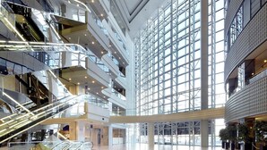 Un atrium à plusieurs niveaux, doté de rampes en verre, d’escalators et d’un espace central ouvert.