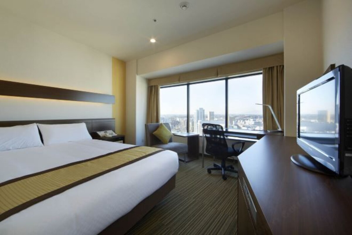 Une chambre d’hôtel avec un grand lit, un bureau avec un ordinateur, une chaise et un téléviseur.