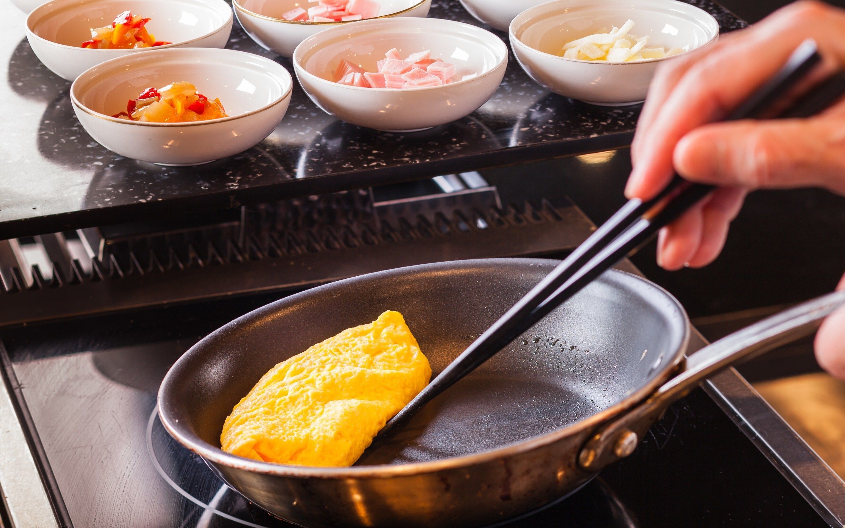 A person cooking an omelette in a pan on a stove.