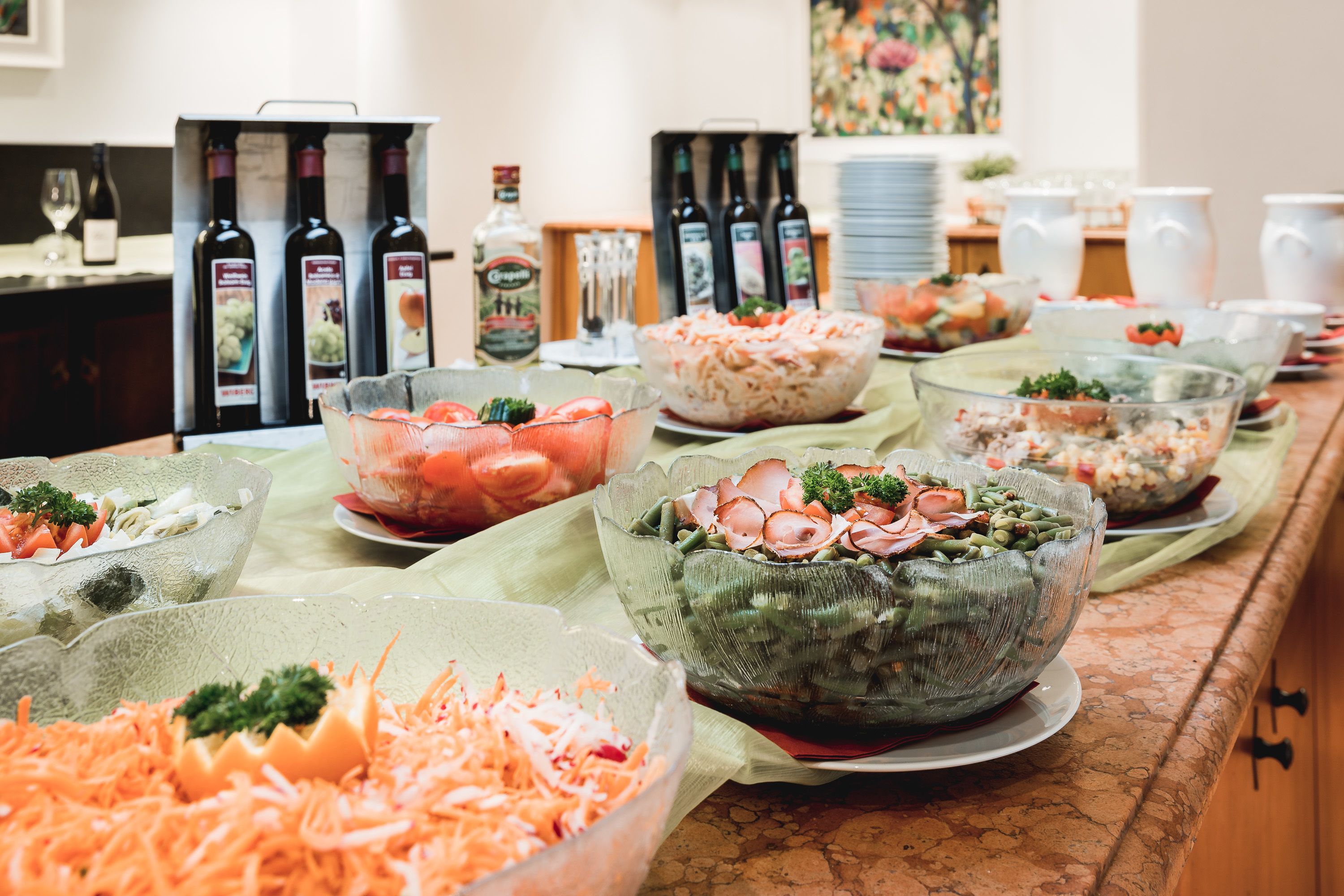 Una mesa de buffet con diversos alimentos y una selección de botellas de vino.