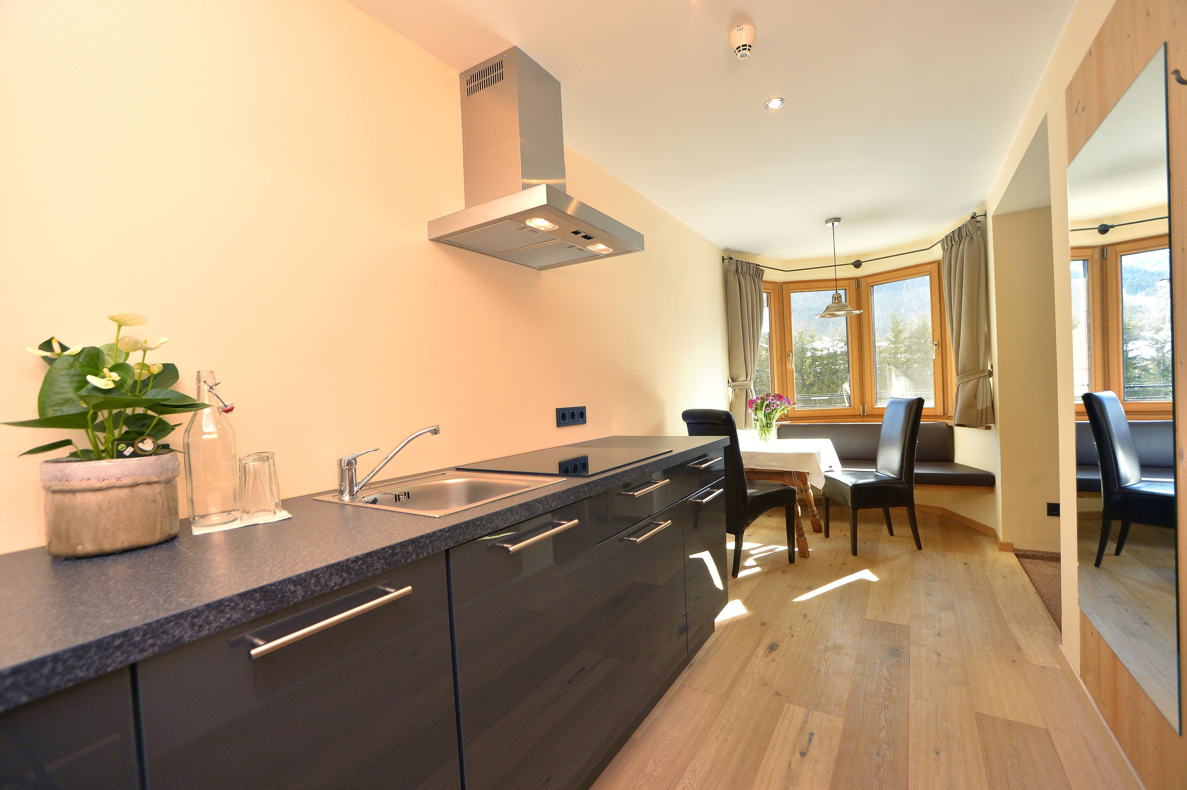 Een moderne keuken met een ingebouwde kookplaat, een spoelbak en een eethoek met een tafel en stoelen.