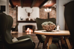 Un rincón comedor acogedor con una mesa redonda de madera, dos sillas tapizadas y un centro de mesa decorativo con una cesta tejida. Hay una vela encendida y una jarras de vidrio sobre la mesa.